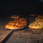 Golden brown bread being baked in a traditional stone oven, showcasing artisanal craftsmanship. - Photo by Yasin Onuş on Pexels