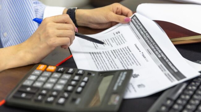 Close-up of a person analyzing financial documents using a calculator and pen. - Photo by Bia Limova on Pexels