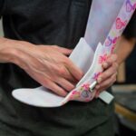 A person designing a vibrant, heart-patterned orthotic brace indoors, showcasing craftsmanship. - Photo by ThisIsEngineering on Pexels