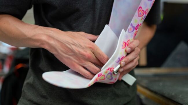A person designing a vibrant, heart-patterned orthotic brace indoors, showcasing craftsmanship. - Photo by ThisIsEngineering on Pexels