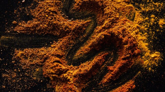 From above of creative design of smoked ground paprika and turmeric mixed together on black surface - Photo by https://kaboompics.com/ on Pexels