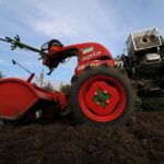 Close-up of a red two-wheeled tractor plowing a rural field, ideal for agricultural themes. - Photo by light wizzi on Pexels