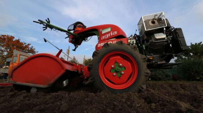 Close-up of a red two-wheeled tractor plowing a rural field, ideal for agricultural themes. - Photo by light wizzi on Pexels